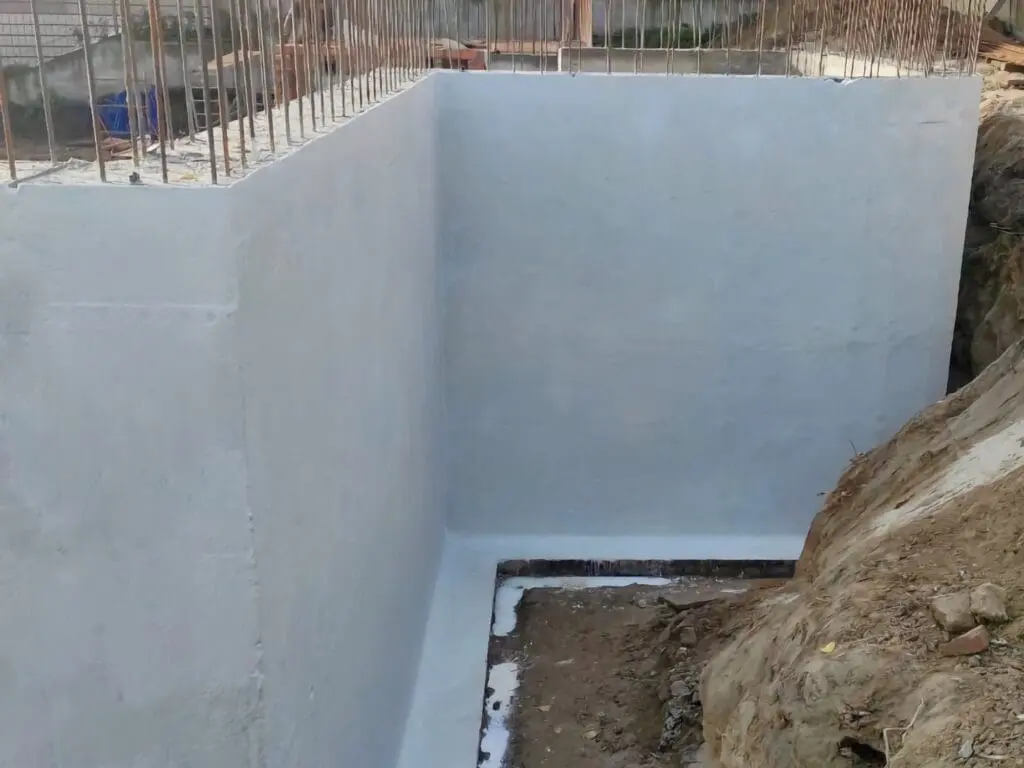 Фото монолітного бетонного фундаменту з ідеально рівною поверхнею та нанесеною полімерцементною гідроізоляцією білого кольору