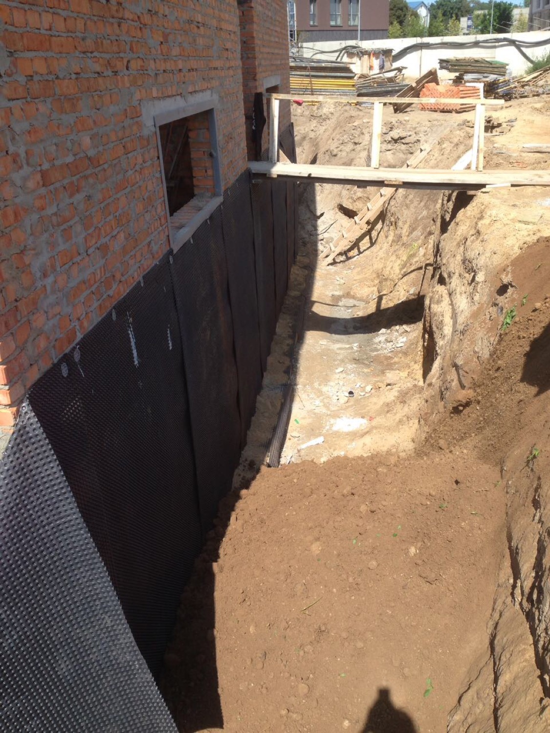 Процес улаштування захисту стін фундаменту після нанесення гідроізоляції