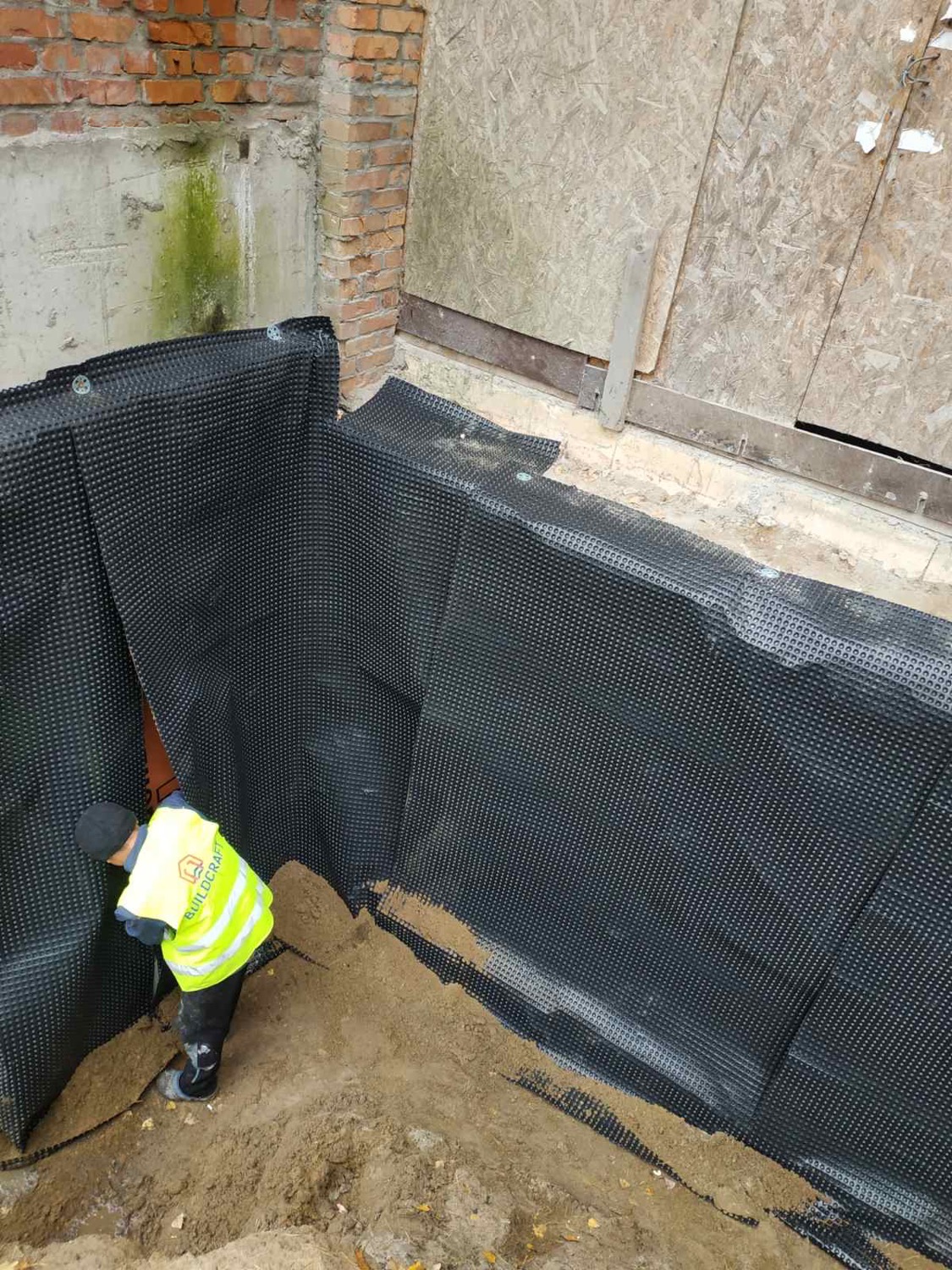Улаштування дренажної мембрани чорного кольору як захисту при зворотній засипці