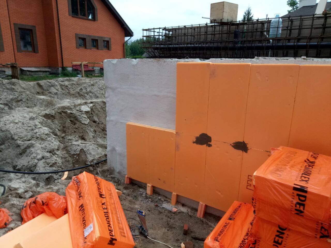 Монтаж утеплення на стіни фундаменту з нанесеною гідроізоляцією