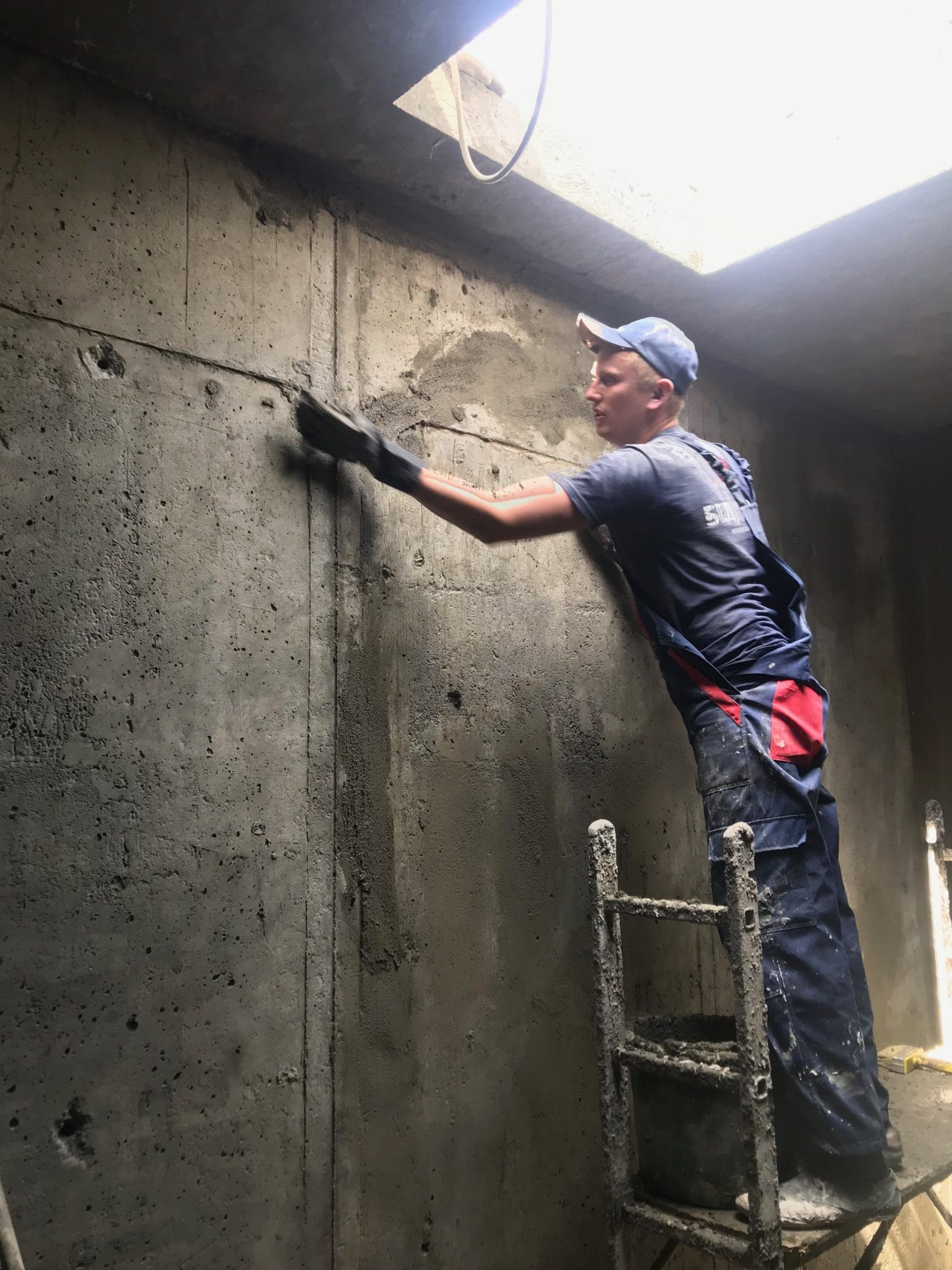 Затирання нерівностей та каверн на стіні фундаменту ремонтним матеріалом