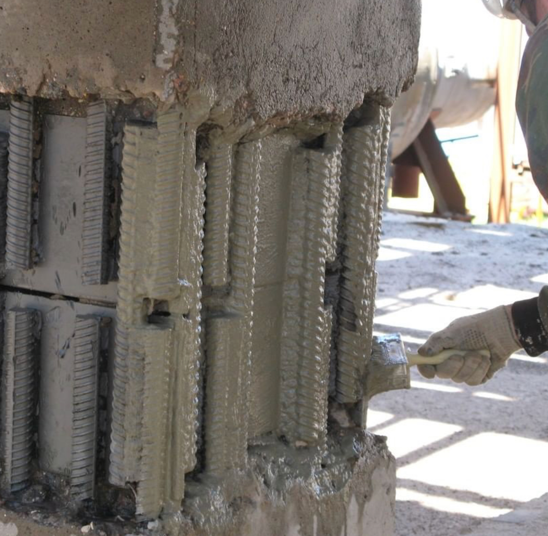 Процес нанесення антикорозійного шару на відкриту арматуру бетонної колони